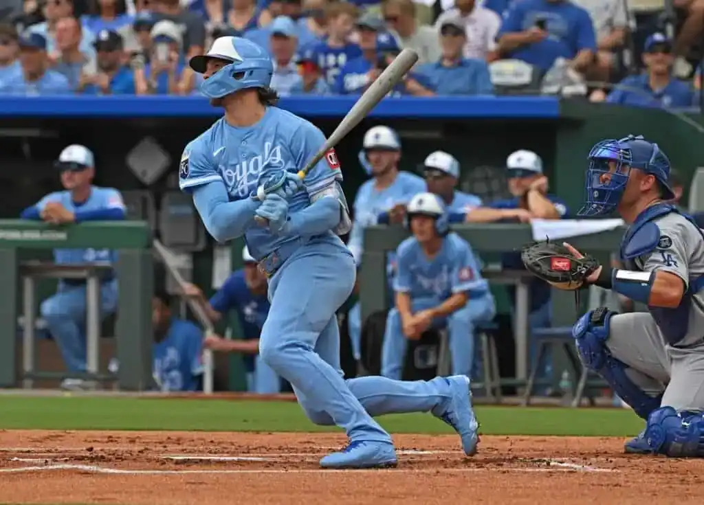 A Kansas City Royals player in a powder blue uniform swings the bat during a game.