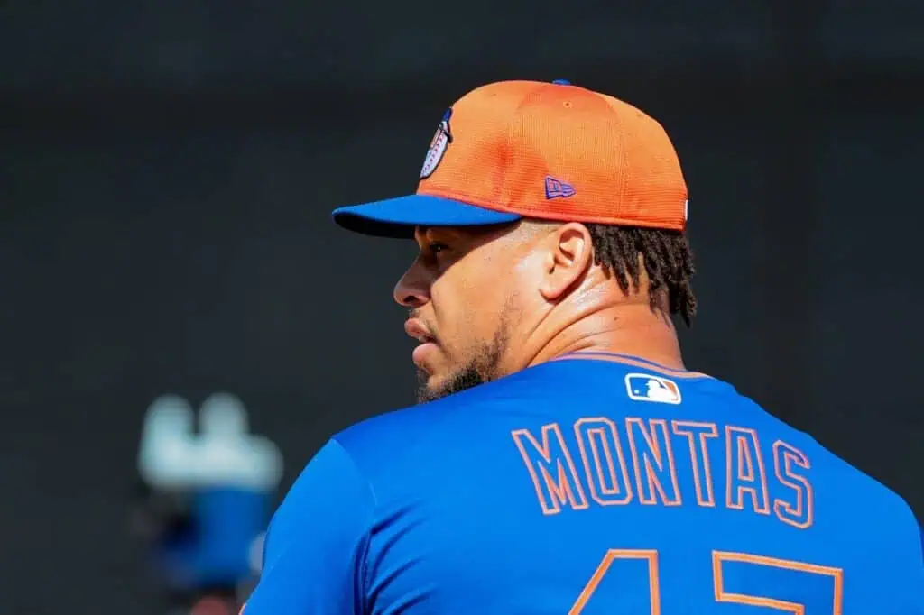 A baseball player wearing a blue jersey with the name "MONTAS" and number 45, alongside an orange cap, stands on a field.