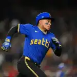 A player in a blue Seattle Mariners jersey sprints confidently across the field during an intense baseball game.