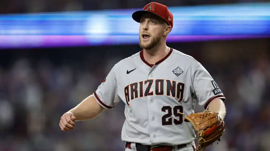 Arizona Diamondbacks vs San Diego Padres Picks and Predictions June 15th 2025 2 A baseball player in a gray Arizona Diamondbacks jersey, wearing a red cap and holding a glove, walks on the field during a game.