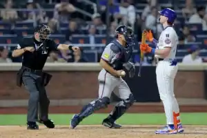 A baseball catcher prepares to throw while the umpire signals, and a batter stands ready, following a tense moment during the game.