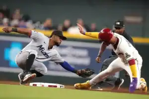 A Miami Marlins infielder attempts to tag out a baserunner who is sliding into the base during a game.