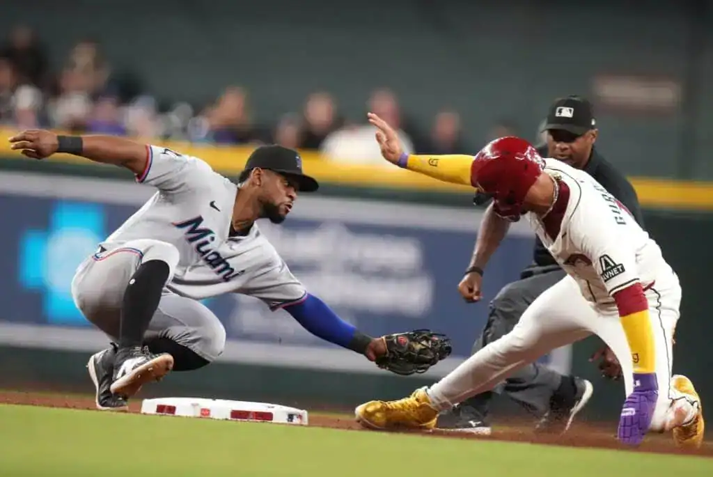 A Miami Marlins infielder attempts to tag out a baserunner who is sliding into the base during a game.