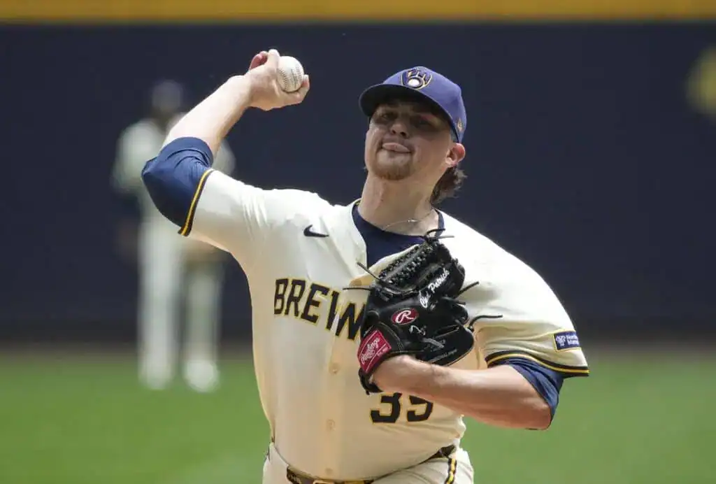 A baseball player in a Brewers uniform prepares to pitch, gripping a baseball