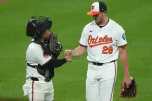 A Baltimore Orioles pitcher and catcher fist bump on the field during a game.