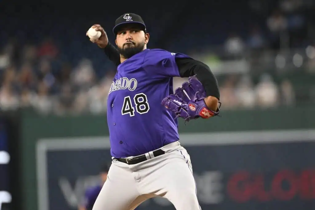A Colorado Rockies pitcher in a purple jersey and cap is in mid-throw, showcasing his focused stance on the baseball field.