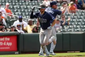 A Tampa Bay Rays player runs the bases while a coach cheers him on during a game.