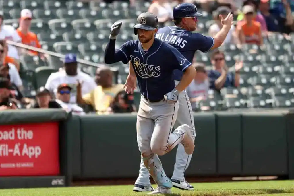 A Tampa Bay Rays player runs the bases while a coach cheers him on during a game.