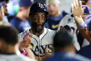 A baseball team celebrates a player's achievement in the dugout, with players giving high-fives