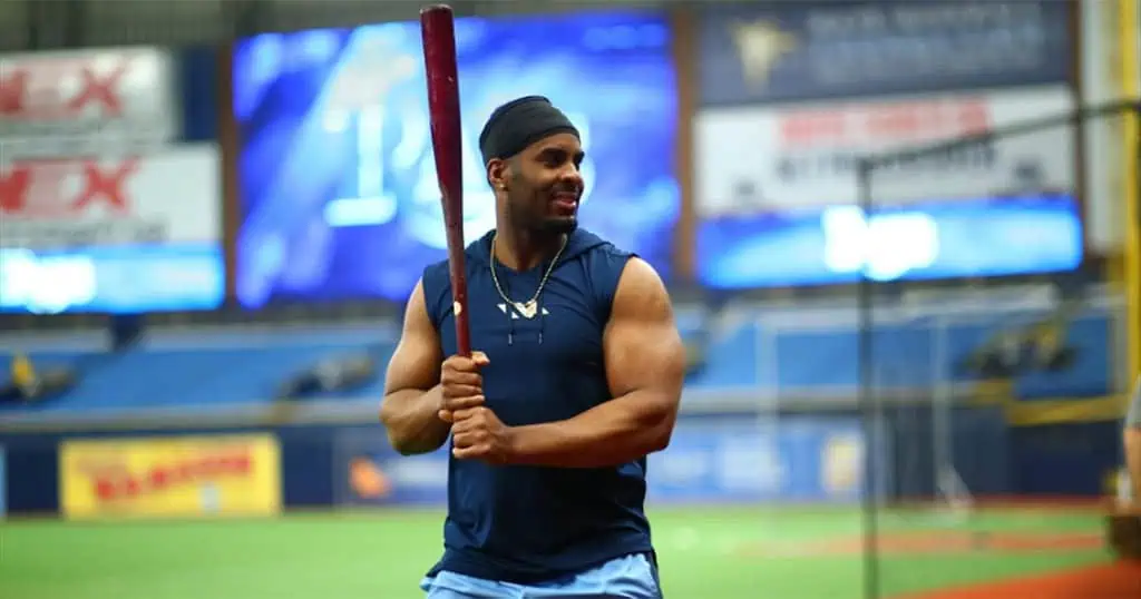 Kansas City Royals vs Tampa Bay Rays Picks and Predictions June 25th 2025 2 A muscular athlete stands ready with a baseball bat in a training facility, vibrant screens and banners visible in the background.