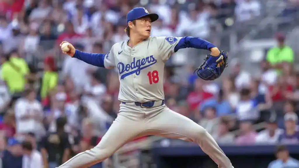 Los Angeles Dodgers vs San Francisco Giants Picks and Predictions June 13th 2025 2 A pitcher in a gray Los Angeles Dodgers uniform winds up to throw, with a crowd of fans visible in the background.