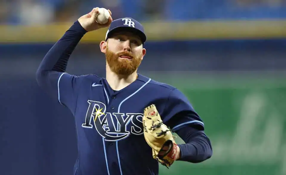 A pitcher in a Tampa Bay Rays uniform prepares to throw a baseball on a sunny day at the stadium, showcasing focused concentration.