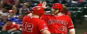 Los Angeles Angels players celebrate with a high five during a game, both wearing red uniforms with number 42 in honor of Jackie Robinson.