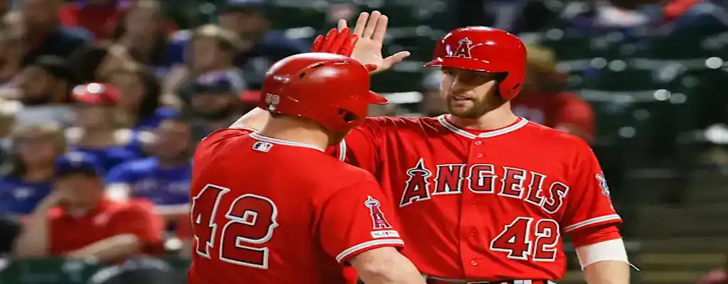 Los Angeles Angels players celebrate with a high five during a game, both wearing red uniforms with number 42 in honor of Jackie Robinson.