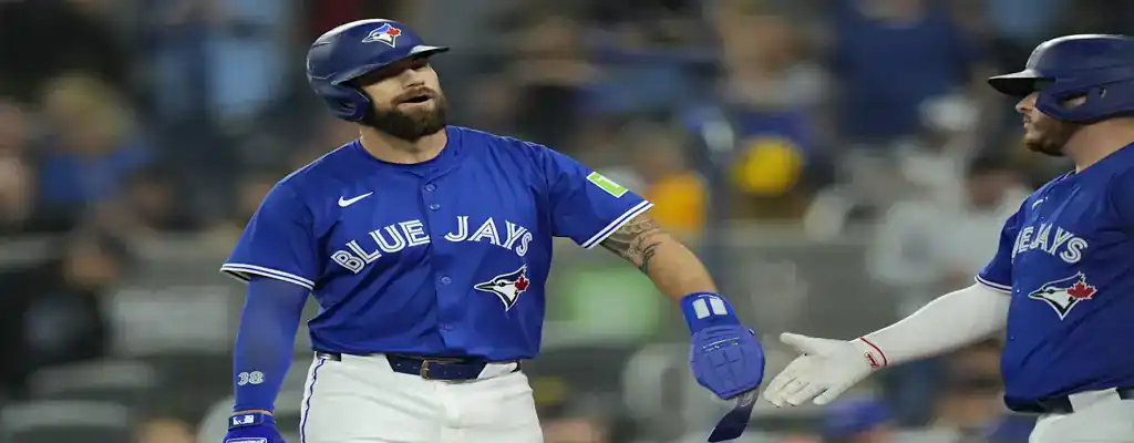 Minnesota Twins vs Toronto Blue Jays Picks and Predictions June 7th 2025 2 Toronto Blue Jays players celebrate a run at home plate, exchanging gestures in blue uniforms during a night game.