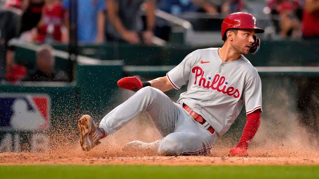 Atlanta Braves vs Philadelphia Phillies Picks and Predictions June 27th 2025 2 Philadelphia Phillies baseball player in a gray uniform and red helmet sliding into a base during a game, kicking up dirt around him.