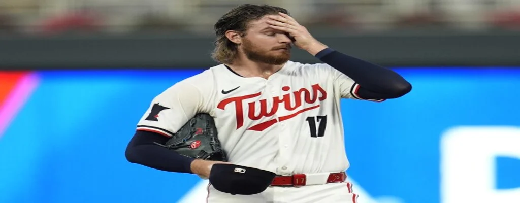 Minnesota Twins vs Seattle Mariners Picks and Predictions June 26th 2025 3 Minnesota Twins pitcher holding his head in frustration during a game, wearing cream uniform with red belt and black glove
