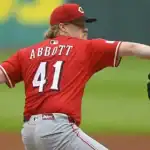 A baseball pitcher in a red jersey, number 41, winds up to throw a pitch on the field, focused and athletic.