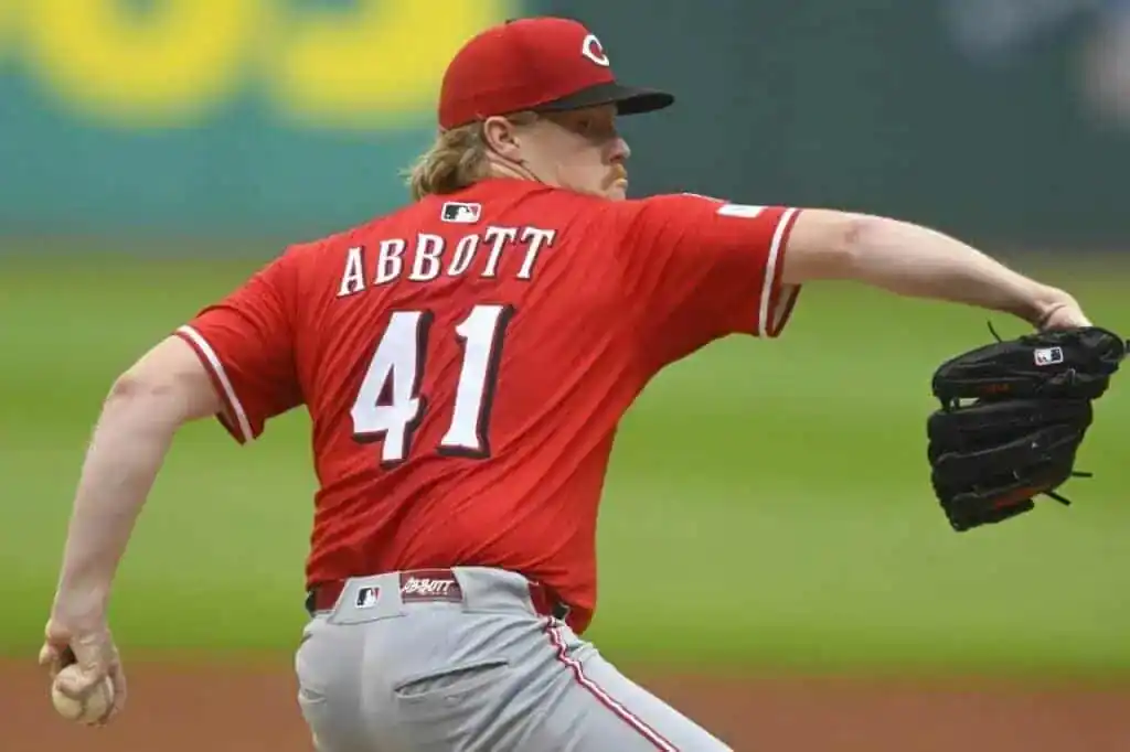 A baseball pitcher in a red jersey, number 41, winds up to throw a pitch on the field, focused and athletic.