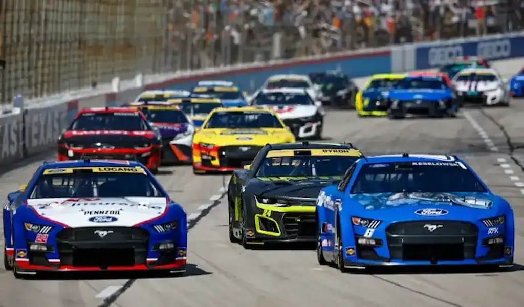 Autos de NASCAR compitiendo en la pista, ilustrando guía experta para apostar en NASCAR