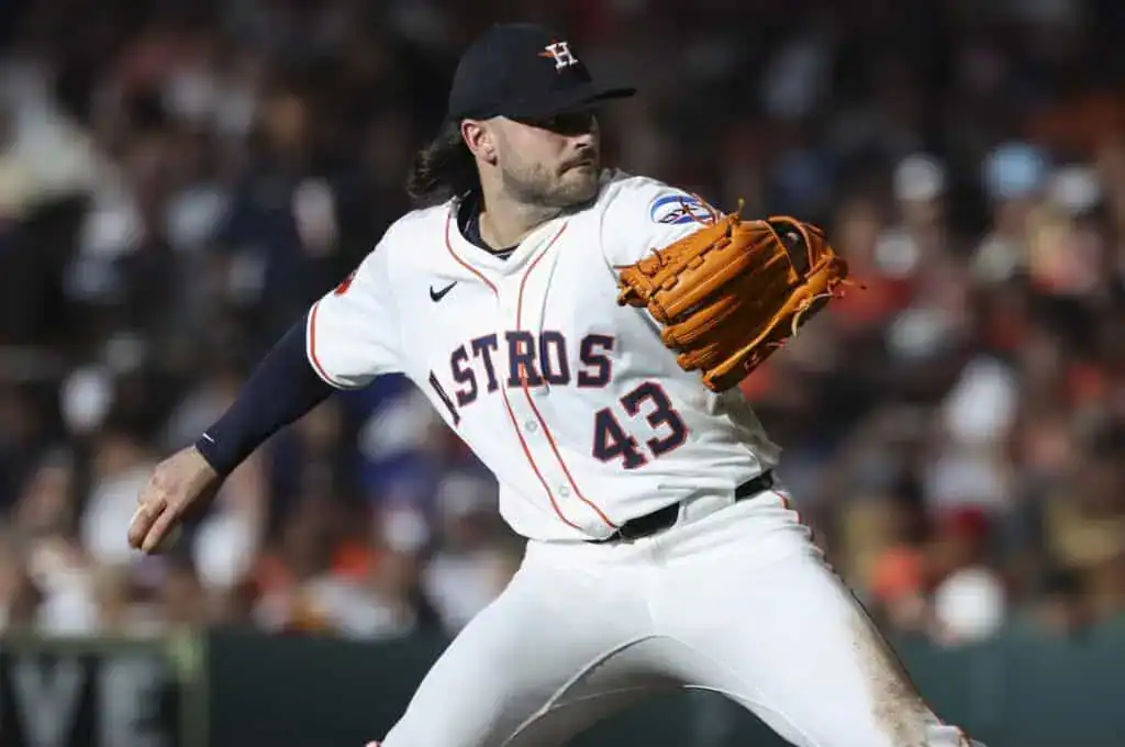 The image features a baseball player in the midst of throwing a baseball. He is wearing a sports uniform and is likely positioned on a baseball field