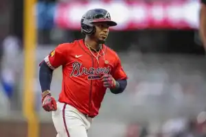 A baseball player in a red Atlanta Braves jersey runs energetically on the field, showcasing determination and passion for the game.