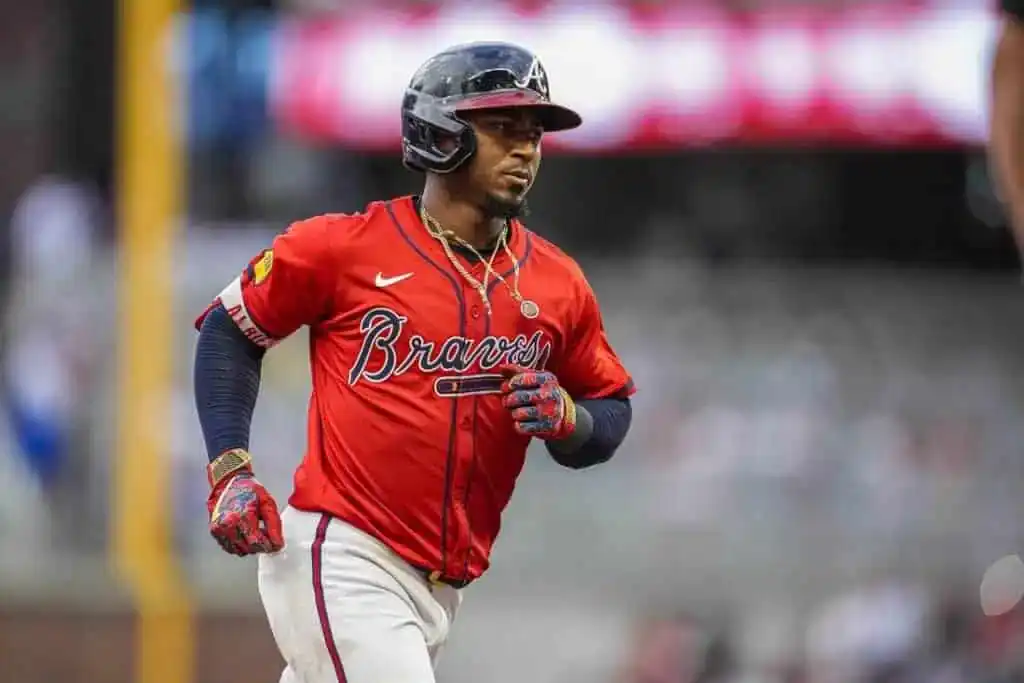5 A baseball player in a red Atlanta Braves jersey runs energetically on the field, showcasing determination and passion for the game.