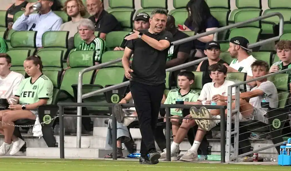 Austin FC coach shouting instructions from the sideline during a match against New England Revolution