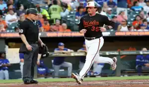 Baltimore Orioles player scores a run as the umpire looks on during a game against the Toronto Blue Jays