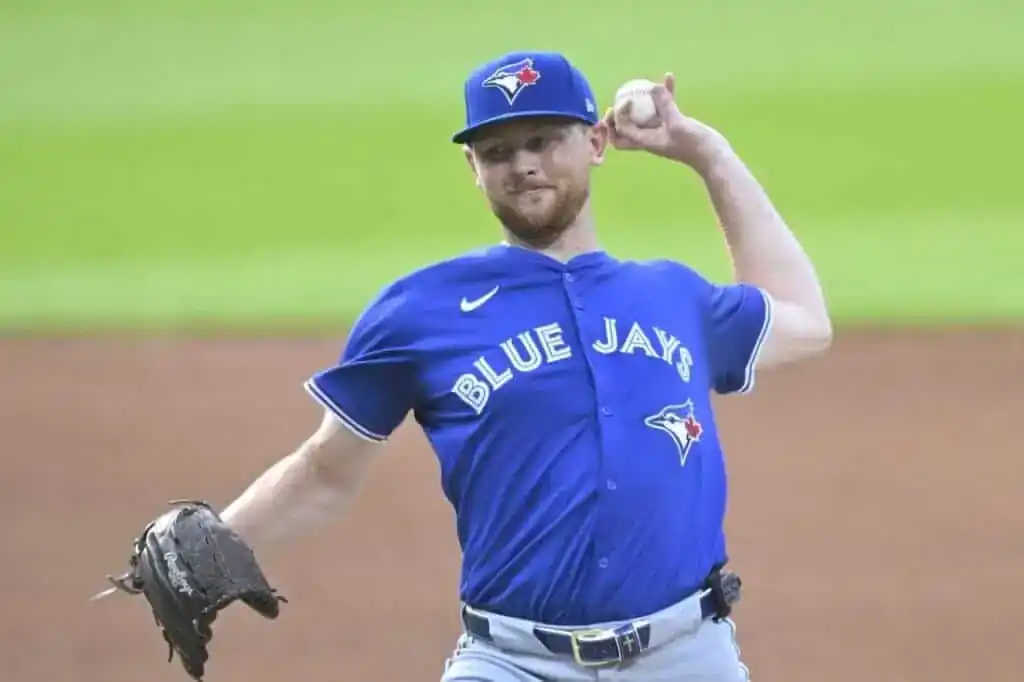 A pitcher wearing a blue Toronto Blue Jays jersey throws a baseball on the field, showcasing a dynamic throwing motion.