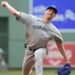 A Toronto Blue Jays pitcher winds up to throw the ball on a baseball field, showcasing dynamic motion and athletic form.