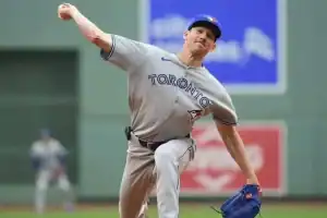 A Toronto Blue Jays pitcher winds up to throw the ball on a baseball field, showcasing dynamic motion and athletic form.