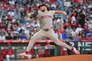 A baseball player is captured mid-action while throwing a ball. The scene takes place in an outdoor stadium, likely during a college baseball game in Boston.