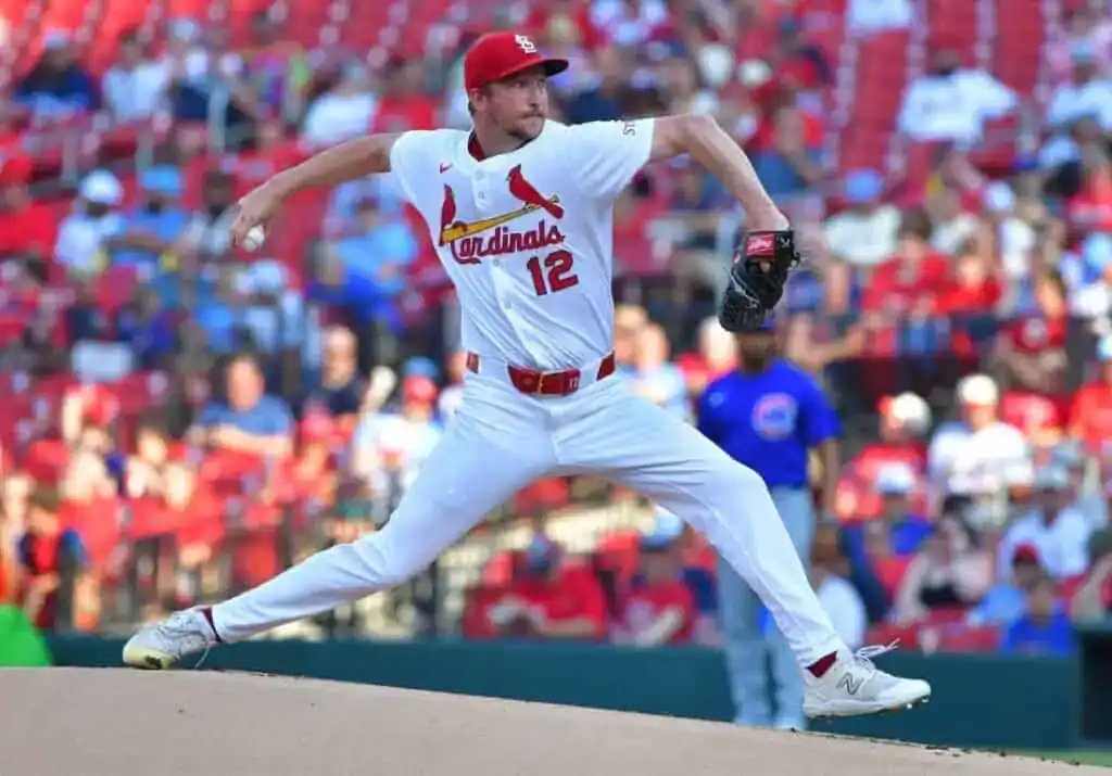 A baseball player, wearing a Cardinals uniform, is captured in the act of throwing a ball. The scene takes place outdoors at a baseball park or stadium during a game.