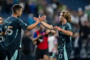 Two men in sports uniforms are joyfully high-fiving each other, celebrating a moment during a game.