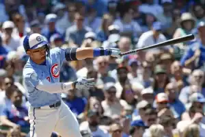 Chicago Cubs player in a light blue City Connect uniform follows through on his swing at bat.