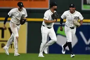 Three Detroit Tigers players smile as they run off the field together.