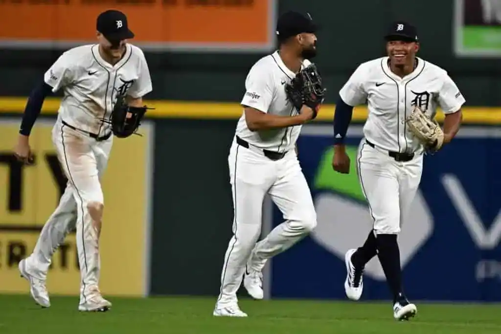 Three Detroit Tigers players smile as they run off the field together.