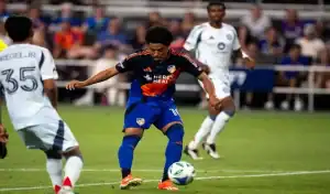 FC Cincinnati player preparing to strike the ball while surrounded by Columbus Crew defenders during a match