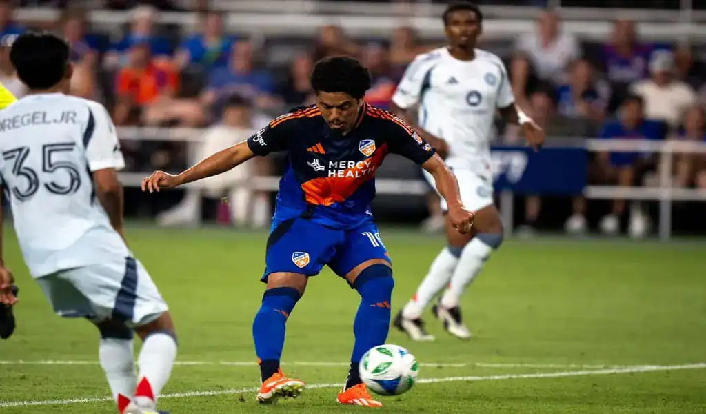 FC Cincinnati player preparing to strike the ball while surrounded by Columbus Crew defenders during a match