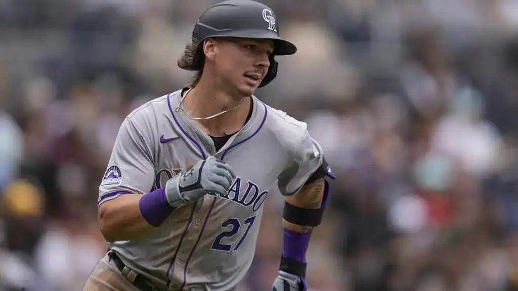 Colorado Rockies player Jordan Beck runs on the basepath in a grey "Colorado" jersey with the number 27.