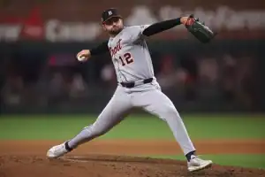 A pitcher in a gray Detroit Tigers uniform winds up to throw a baseball on the field, showcasing athleticism and focus.