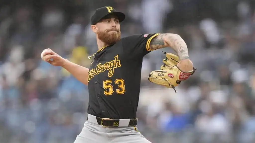 A baseball pitcher from the Pittsburgh Pirates is in action, preparing to throw a pitch wearing a black and gold jersey.