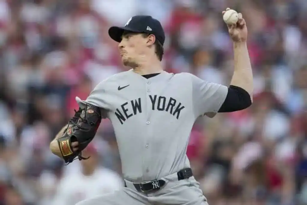 A baseball player in a gray New York Yankees uniform winds up to pitch, showcasing a detailed glove and dynamic posture.