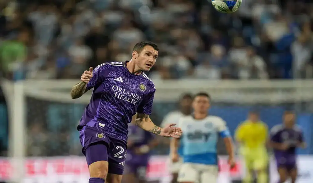 Orlando City player focusing on the ball in mid-air during a match against CF Montréal
