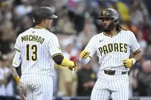 Two baseball players in pinstriped uniforms celebrate a home run during a game, with one player giving a fist bump to the other.