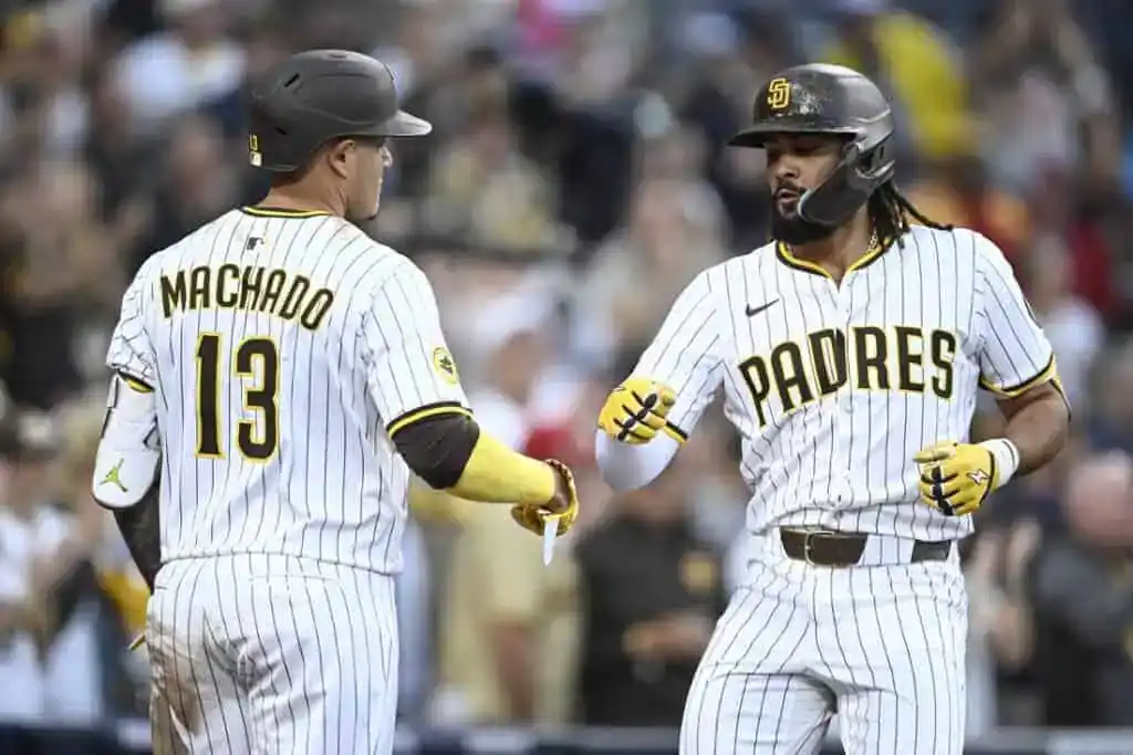 3 Two baseball players in pinstriped uniforms celebrate a home run during a game, with one player giving a fist bump to the other.