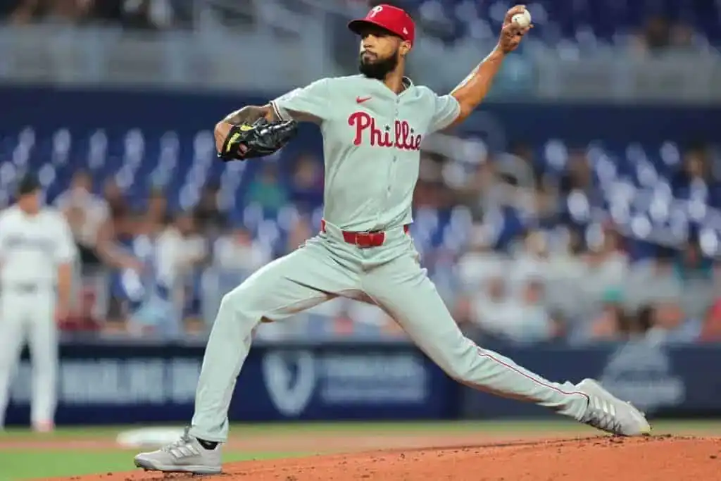 A pitcher in gray Philadelphia Phillies uniform winds up to throw a baseball during a night game at the stadium.