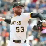 A Pittsburgh Pirates pitcher in mid-throw, wearing a white jersey with black and gold accents, showcasing intense focus on the mound.