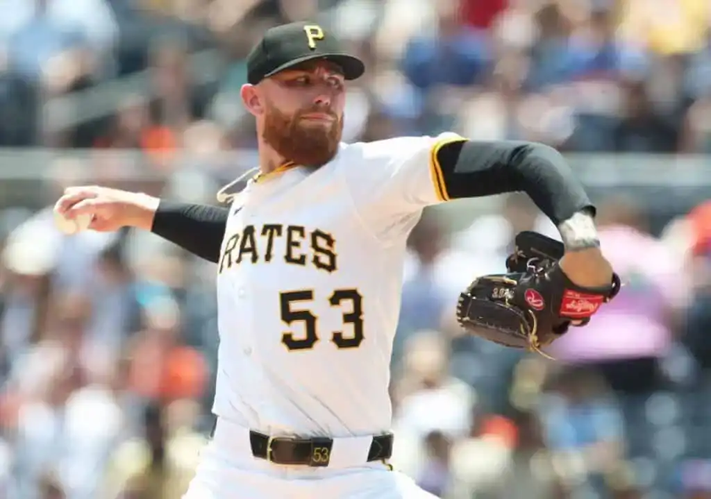 A Pittsburgh Pirates pitcher in mid-throw, wearing a white jersey with black and gold accents, showcasing intense focus on the mound.